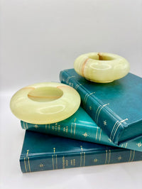 Two green jade rings on top of blue books with gold text on a white background