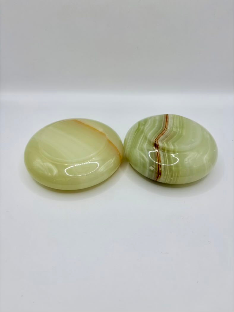 Two green onyx stones with brown veins on a white background