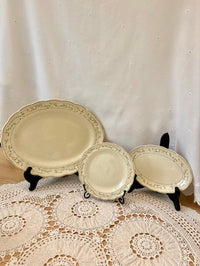 Set of three decorative plates on stands against a white curtain background