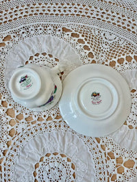 White ceramic teacup and saucer with floral design on a lace tablecloth