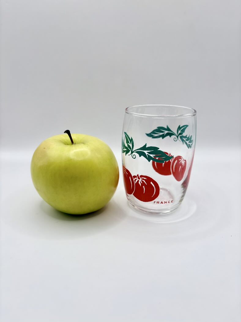 One glass shown against a white background and an apple aside it
