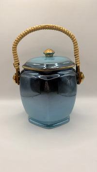 Blue ceramic jar with a woven handle on a white background