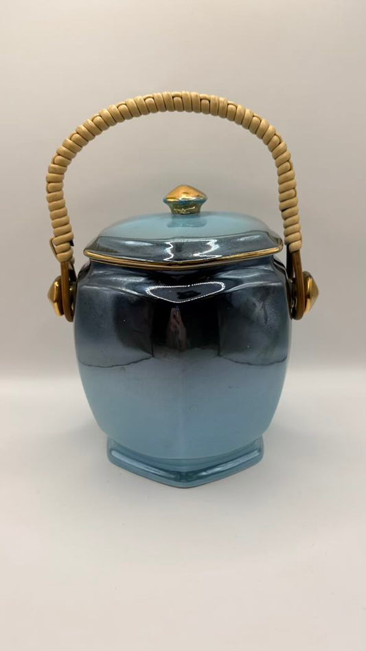 Blue ceramic jar with a woven handle on a white background