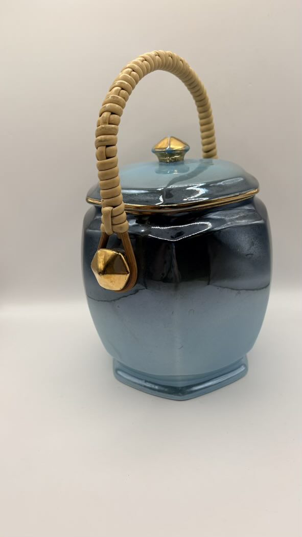 Blue ceramic jar with a gold lid and handle on a white background
