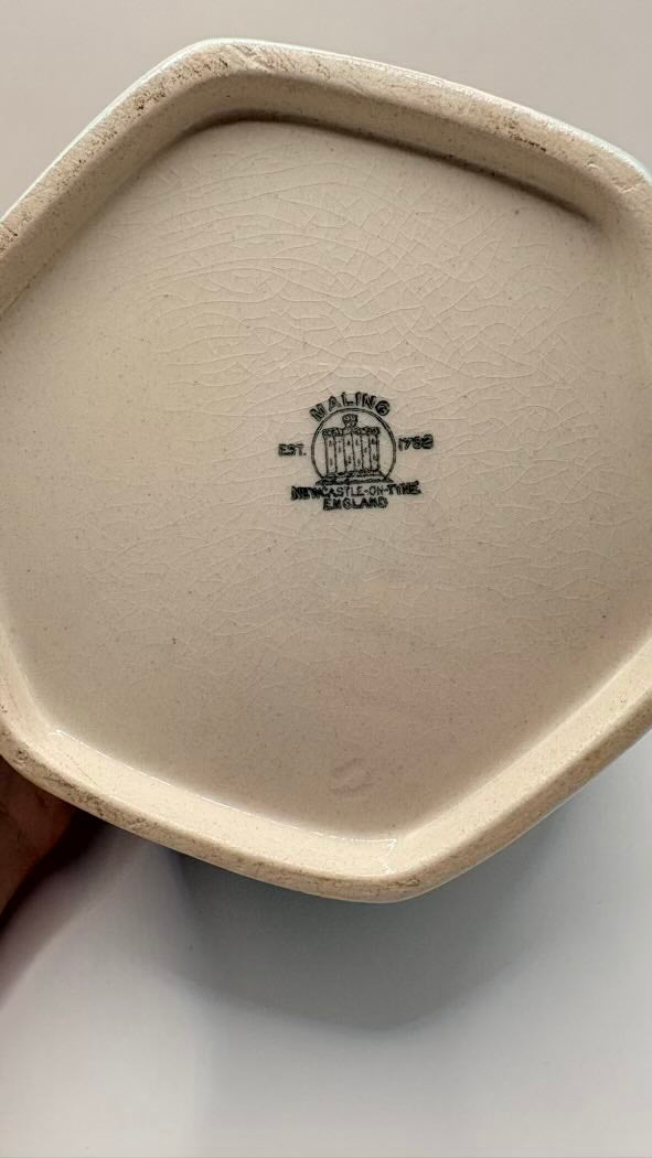 Close-up of a ceramic dish with a logo on a light gray background