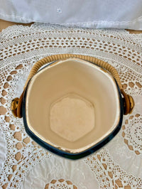 Hexagonal ceramic jar with wooden handles on a lace tablecloth