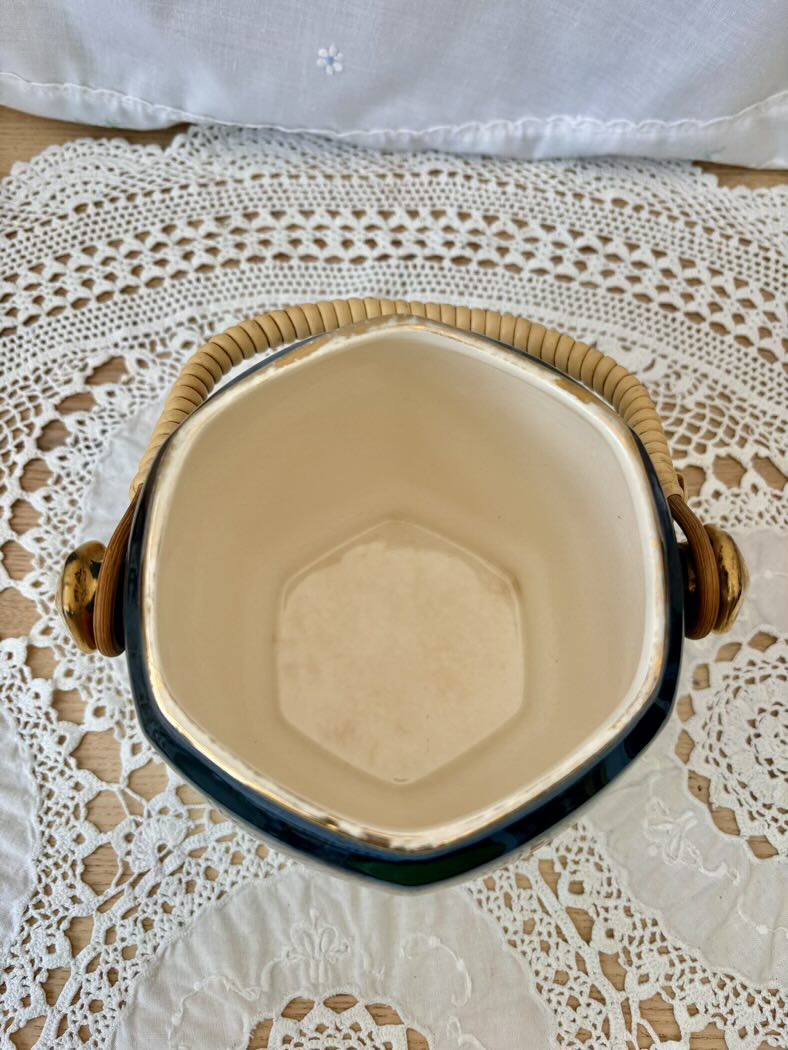 Hexagonal ceramic jar with wooden handles on a lace tablecloth
