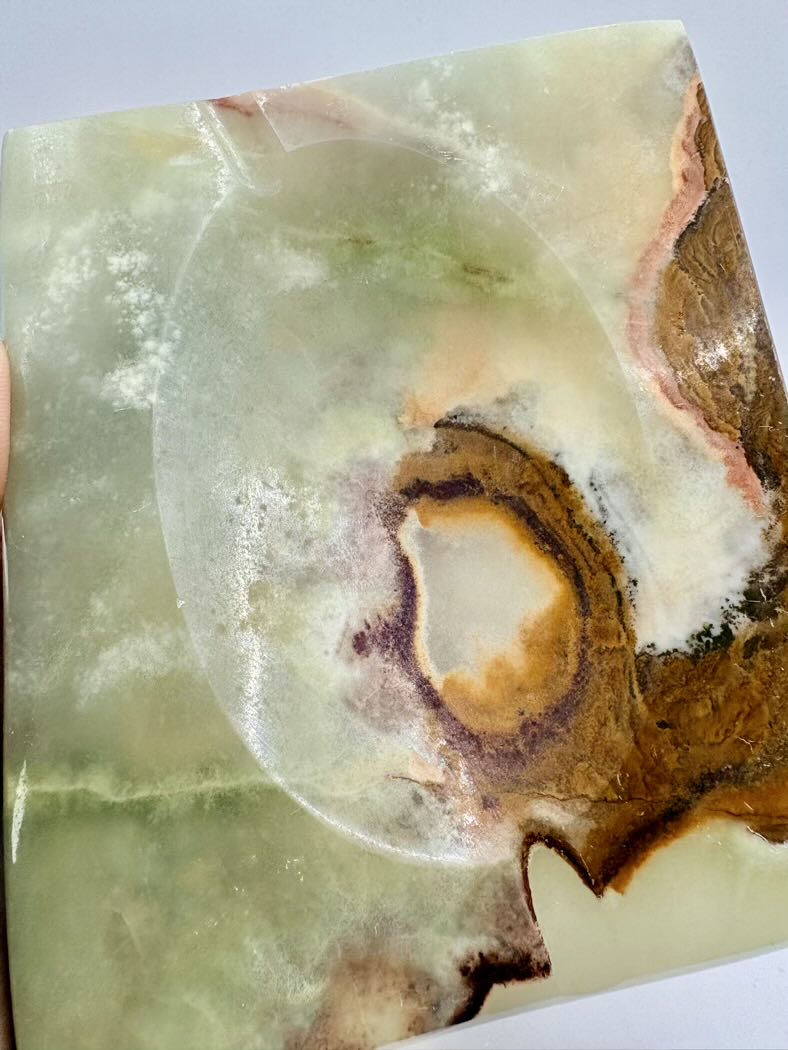 Close-up of a polished stone with a marbled pattern on a light gray background