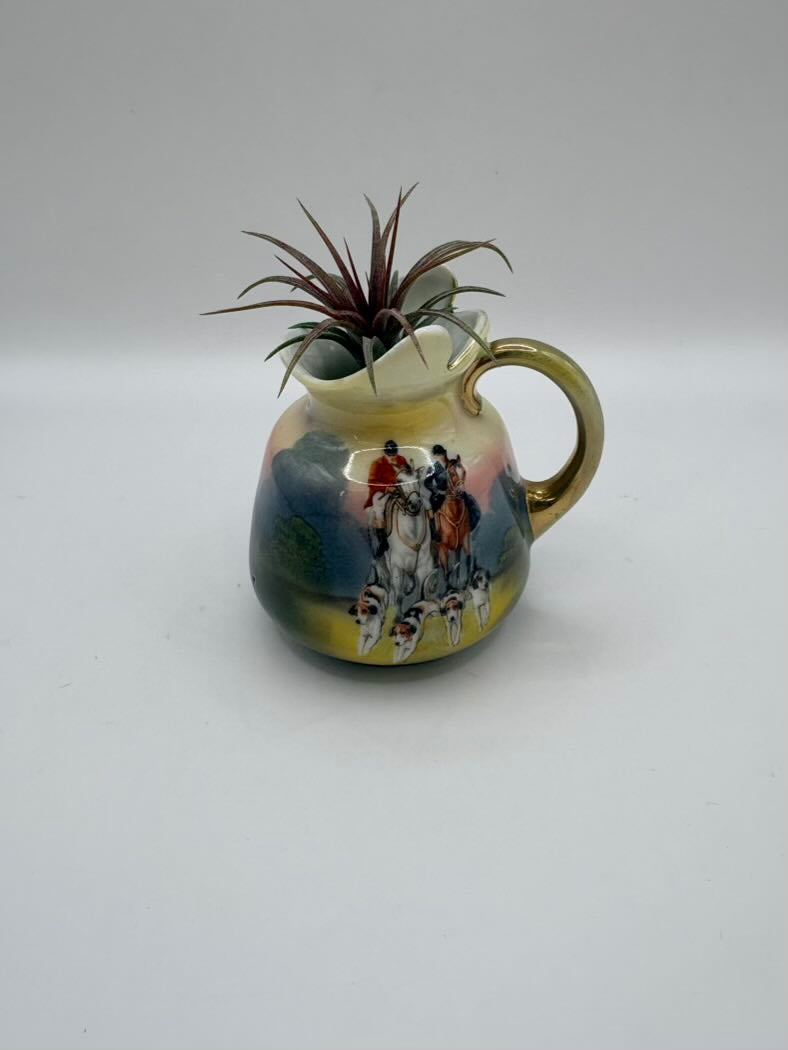 Ceramic pitcher with a decorative design on a plain background