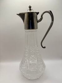 Clear glass carafe with silver metal lid and handle on a white background