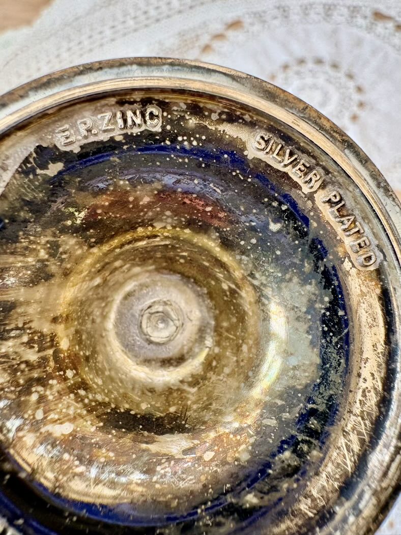 Close-up of a silver-plated object with 'Erving' branding on a textured surface.