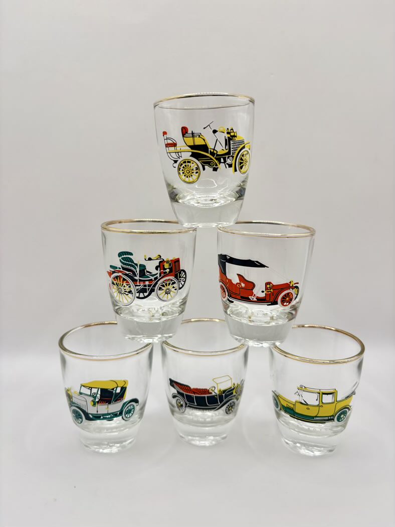 Set of six shot glasses with vintage car designs on a white background