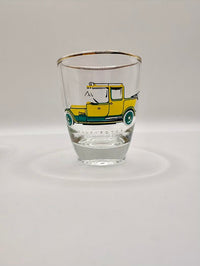 Clear shot glass with a yellow car illustration on a white background