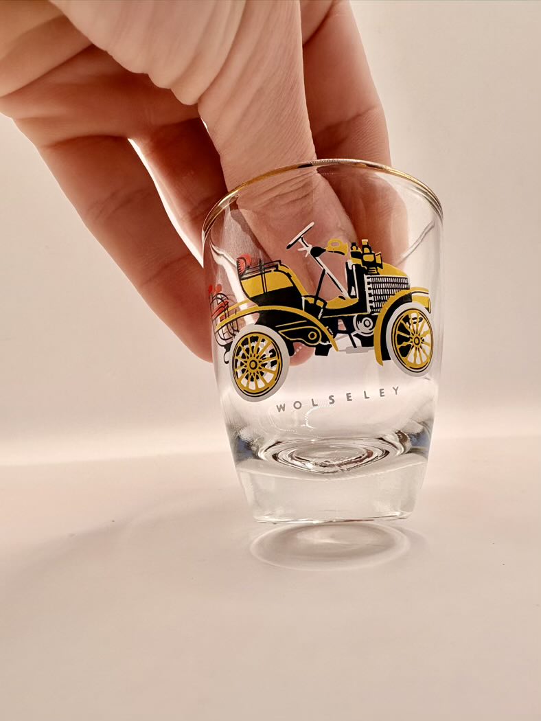 Clear glass with vintage car design held by a hand on a light background