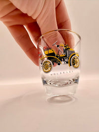 Clear glass with vintage car design held by a hand on a light background