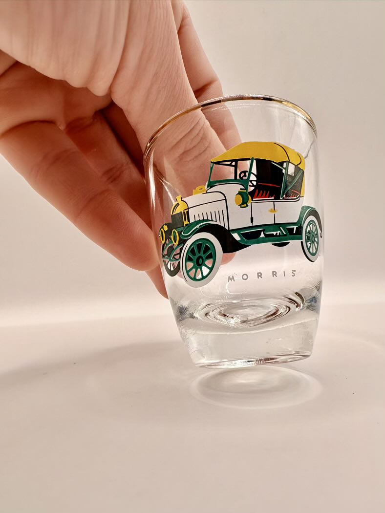 Clear glass with vintage car design held by a hand on a light background
