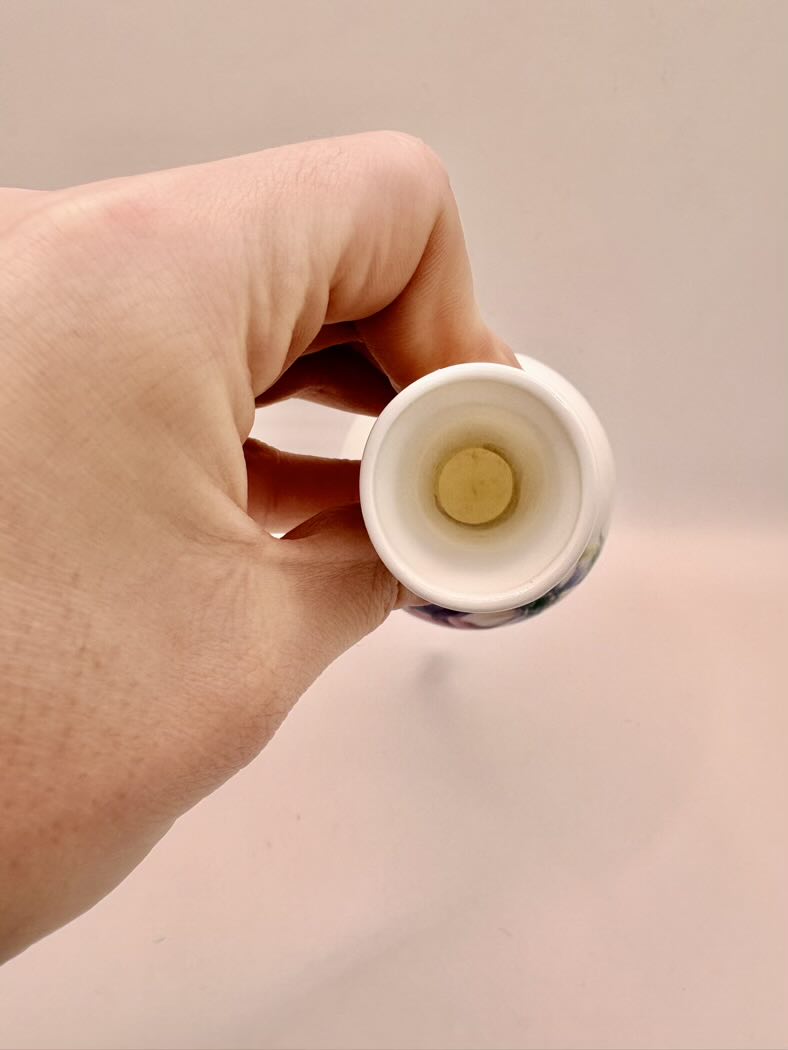 Hand holding a small white container with a yellow object inside against a beige background
