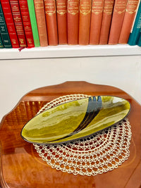 Green ceramic plate on a wooden surface with books in the background