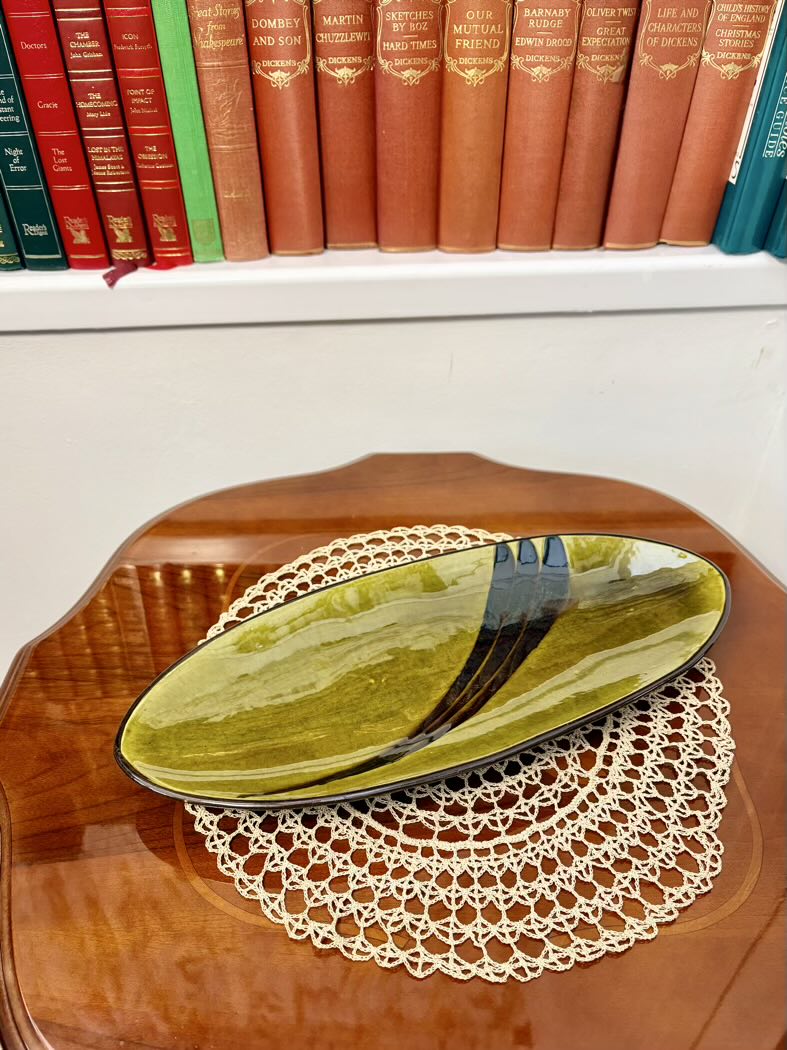Green ceramic plate on a wooden surface with books in the background