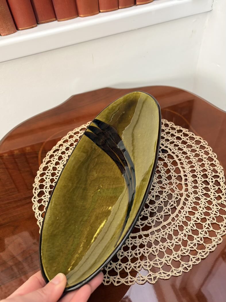 Green ceramic tray inside a box held by a hand on a lace doily
