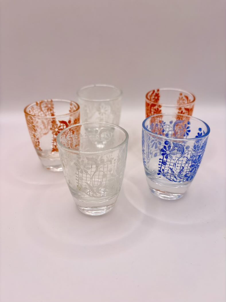 Set of five glass tumblers with different designs on a white background