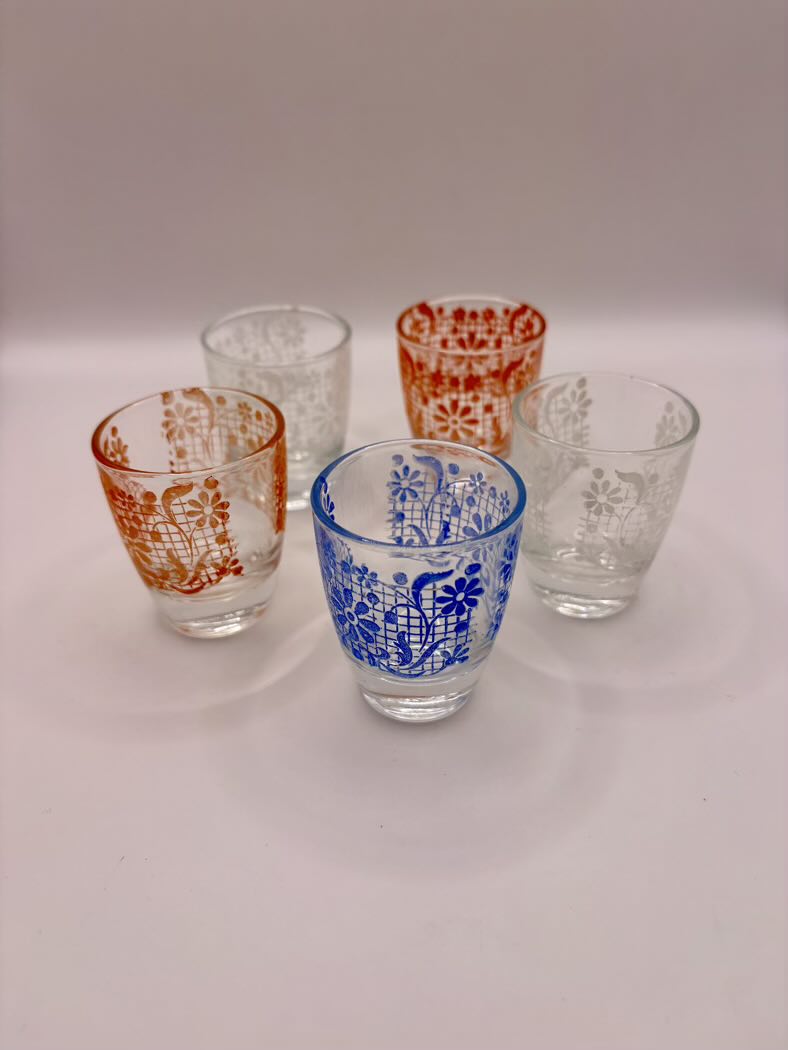 Set of five glass tumblers with floral patterns on a white background