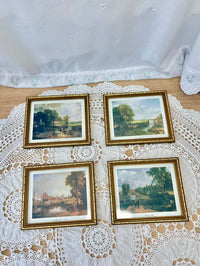 Four framed landscape paintings on a lace tablecloth