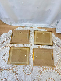 Four back paintings on a lace tablecloth with a white curtain in the background