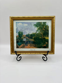 Framed painting of a landscape with trees and people on a white background