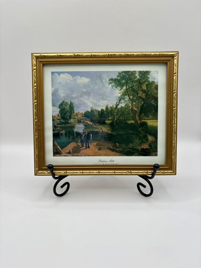 Framed painting of a landscape with trees and people on a white background
