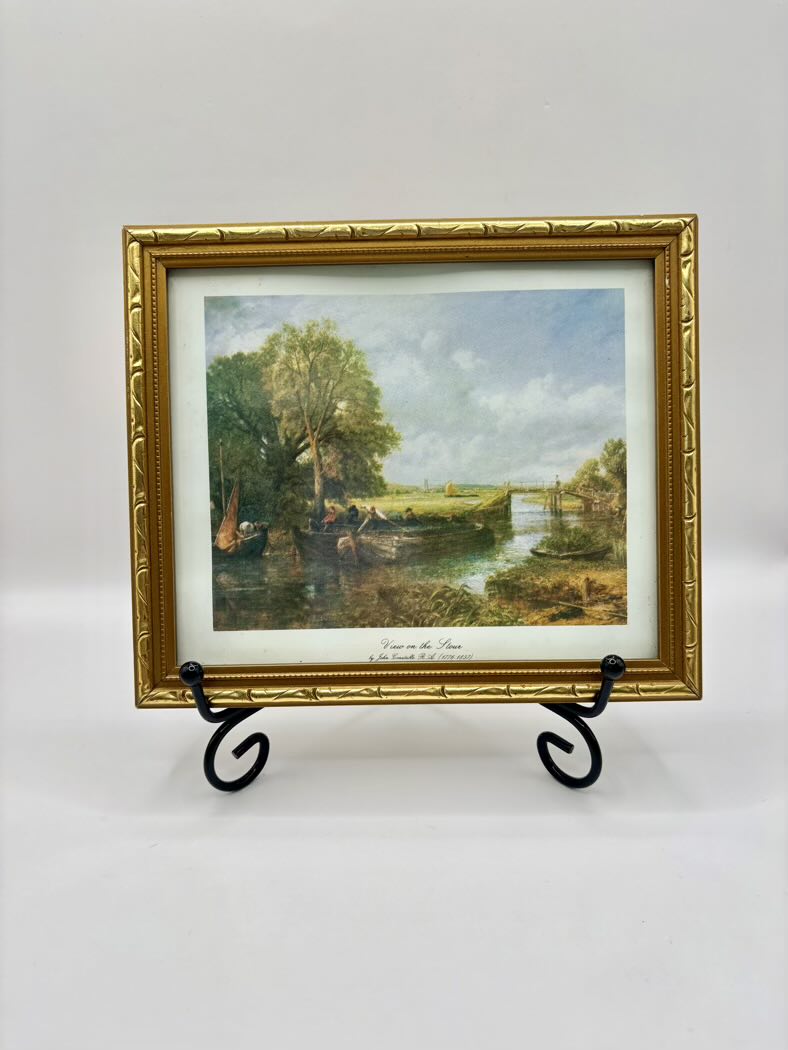 Framed painting of a landscape with a river and trees on a white background