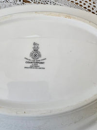 White ceramic plate with a visible brand logo and text on a textured surface.
