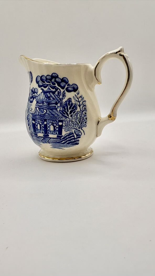White ceramic creamer with blue floral patterns on a white background