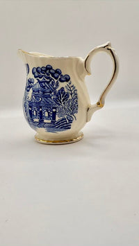 White ceramic creamer with blue floral patterns on a white background