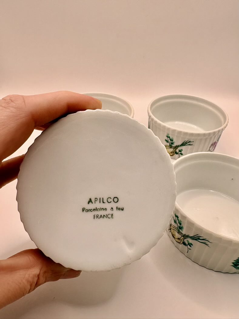 White ceramic lid with 'Apilco' branding held by a hand against a light background.