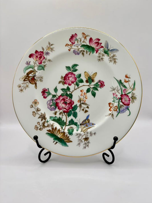 Decorative plate with floral and butterfly design on a stand against a white background