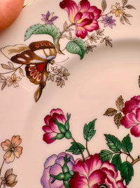 Close-up of a floral and butterfly design on a ceramic surface.