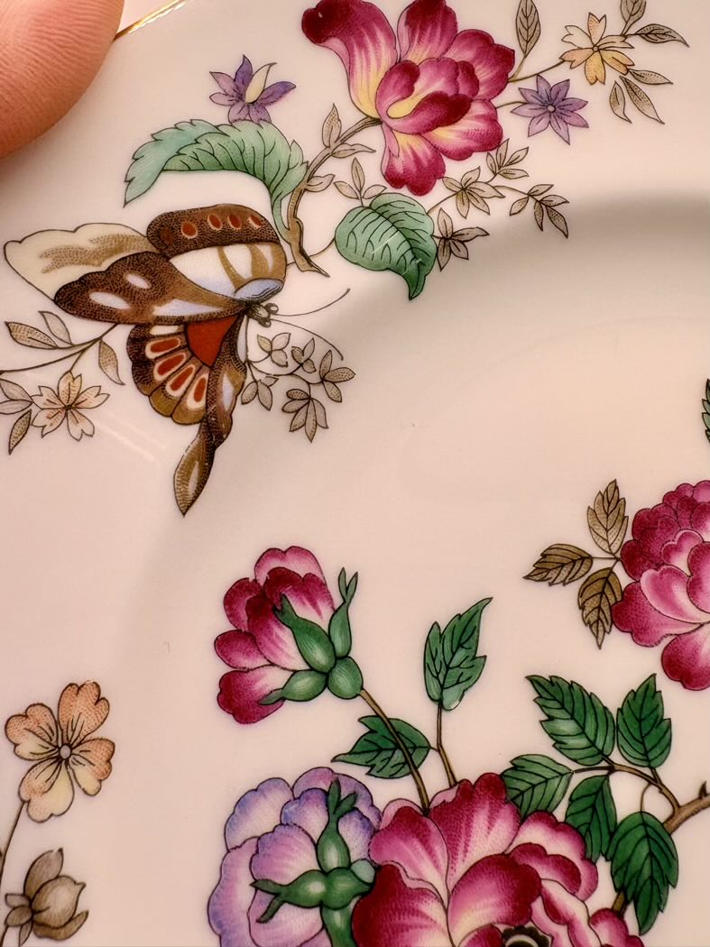 Close-up of a floral and butterfly design on a ceramic surface.