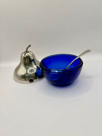 Blue glass bowl with a spoon and silver bell on a white background