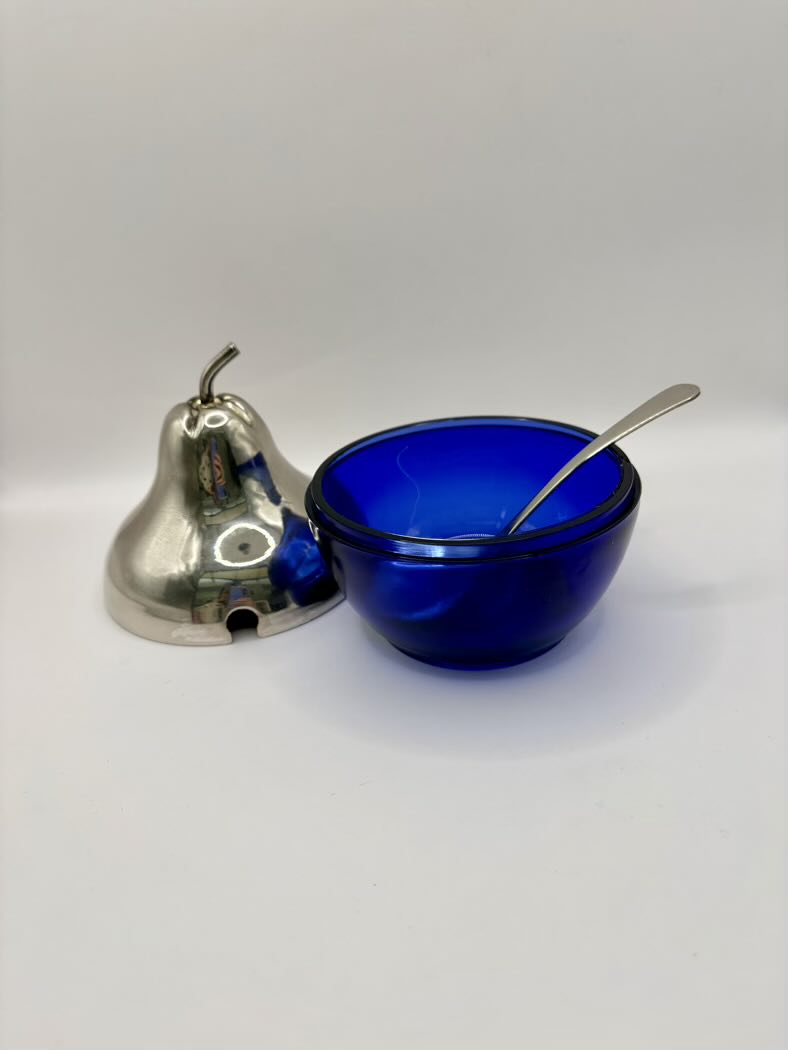 Blue glass bowl with a spoon and silver bell on a white background
