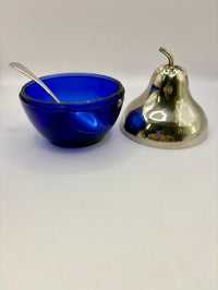 Blue glass bowl with a spoon and metallic bell on a white background