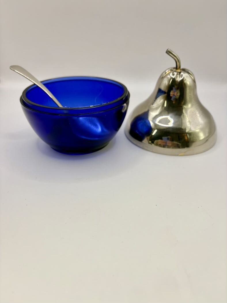 Blue glass bowl with a spoon and metallic bell on a white background