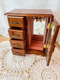 Wooden jewelry cabinet with open door on a lace tablecloth