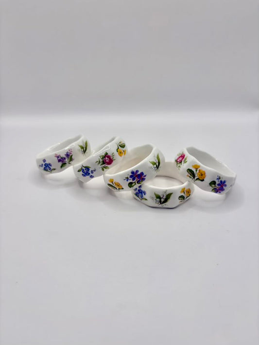 Set of five floral-patterned napkin rings on a white background