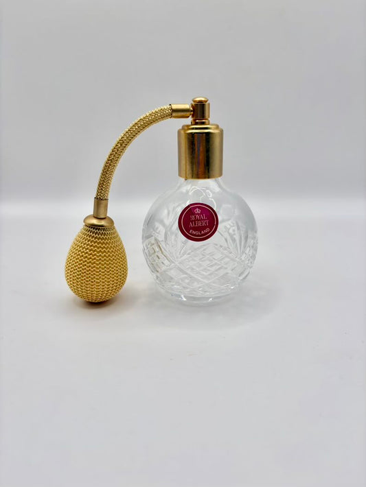 Perfume bottle with gold nozzle and clear glass body on a white background