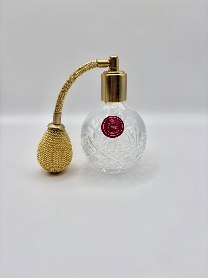 Perfume bottle with gold nozzle and clear glass body on a white background