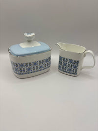 Ceramic sugar bowl and milk pitcher with blue floral pattern on a white background