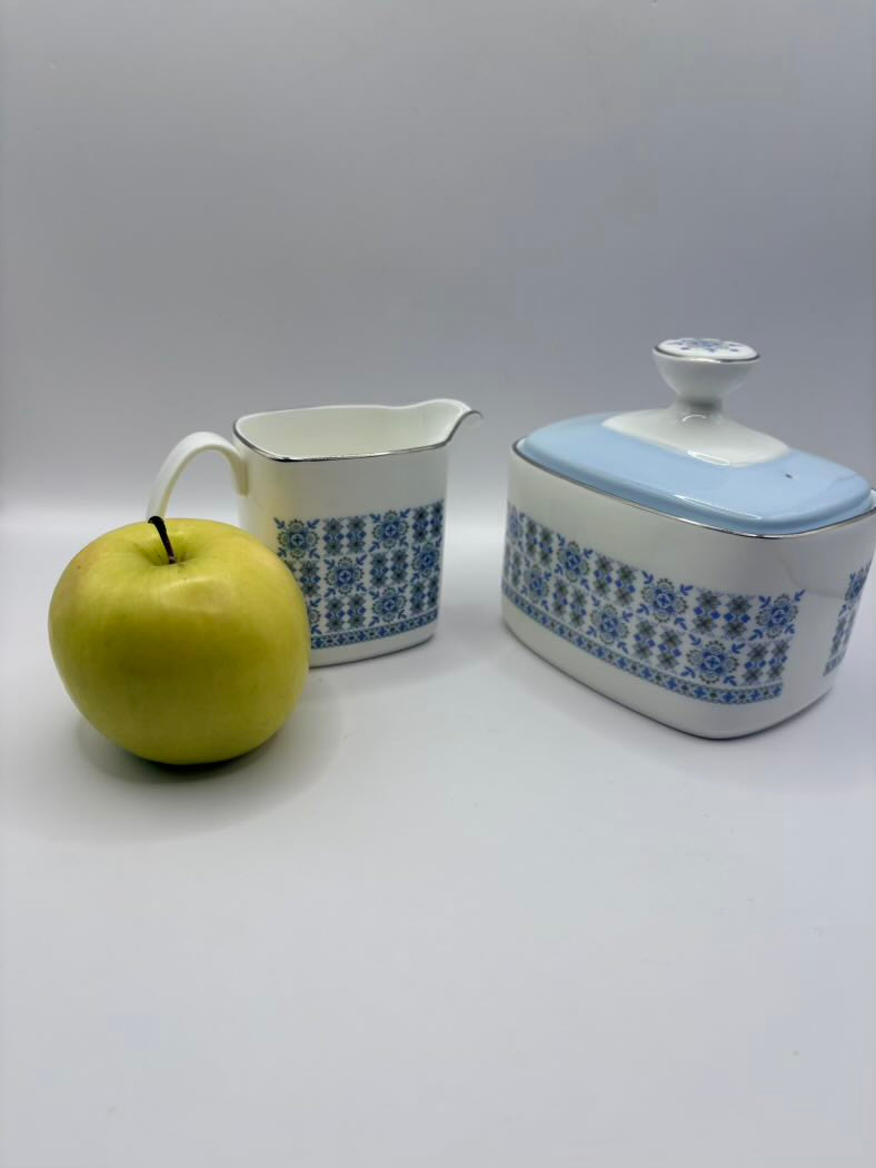 Two ceramic containers with blue floral patterns and a green apple on a white background