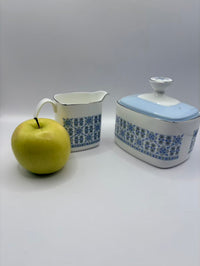 Two ceramic containers with blue floral patterns and a green apple on a white background