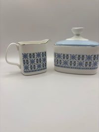 White ceramic creamer and sugar bowl with blue floral pattern on a gray background